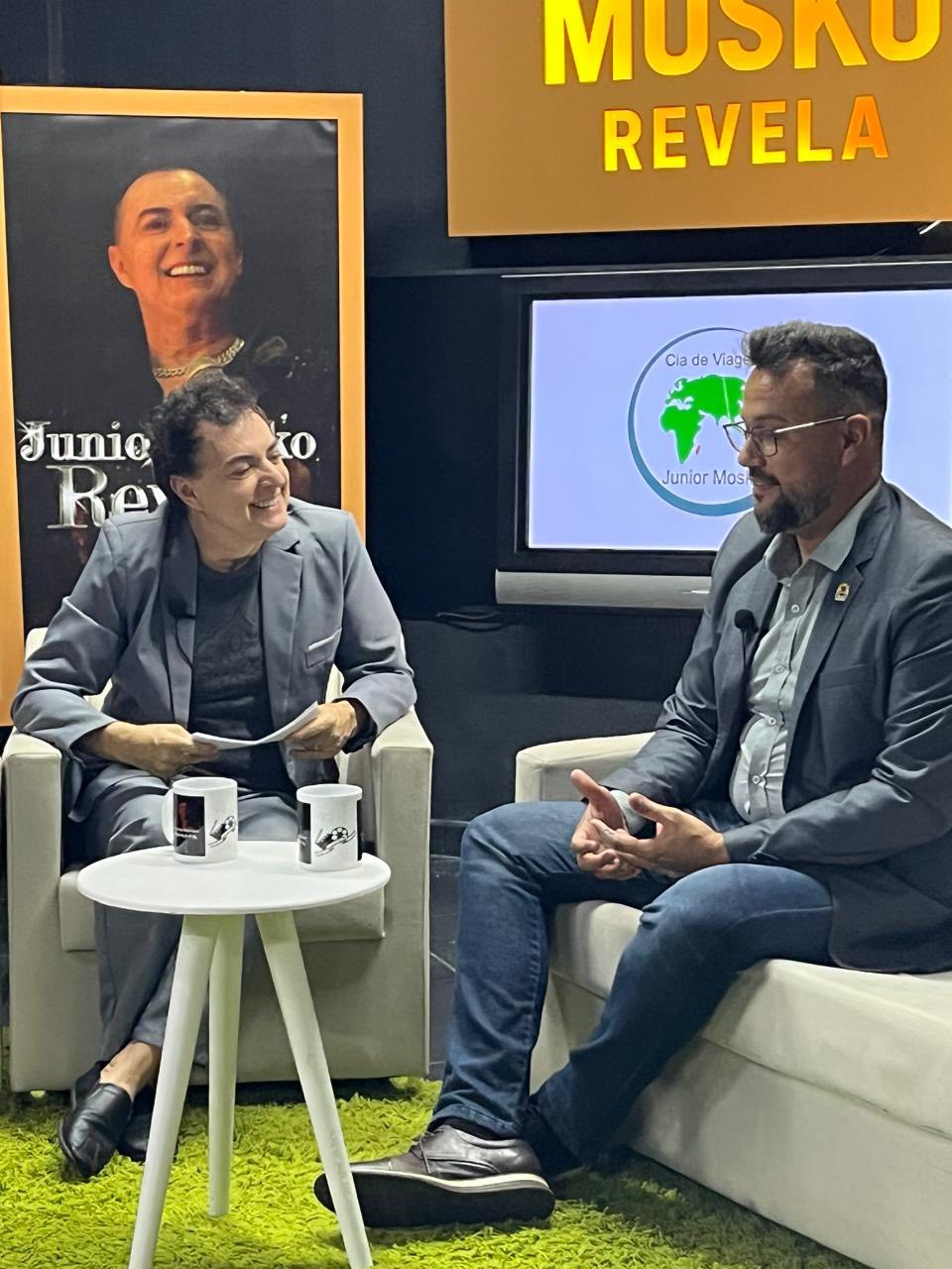 Pode ser uma imagem de 2 pessoas, sala de redação e texto que diz "MUSAU REVELA Clad deViag Viage TO ัอ Re JunlorMos Junior MOs"